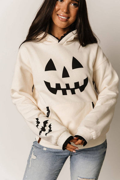 Person wearing a white hoodie with Halloween-themed design on a plain background