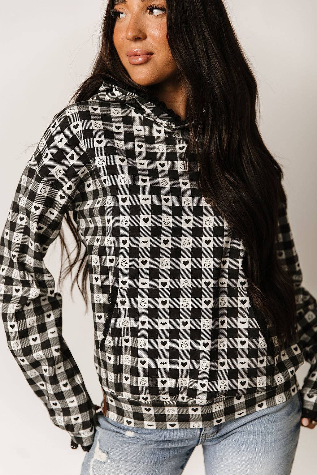 Woman wearing a black and white checkered shirt with heart patterns on a plain background
