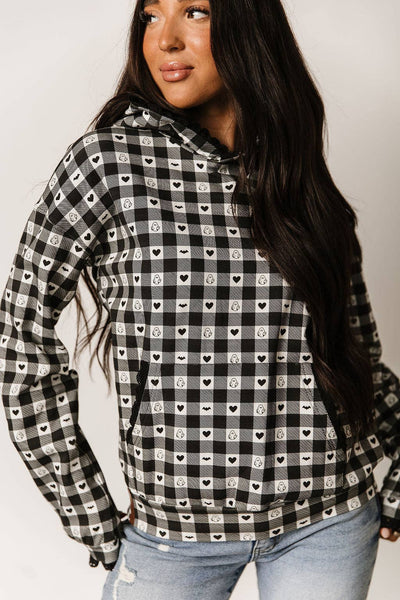 Woman wearing a black and white checkered shirt with heart patterns on a plain background