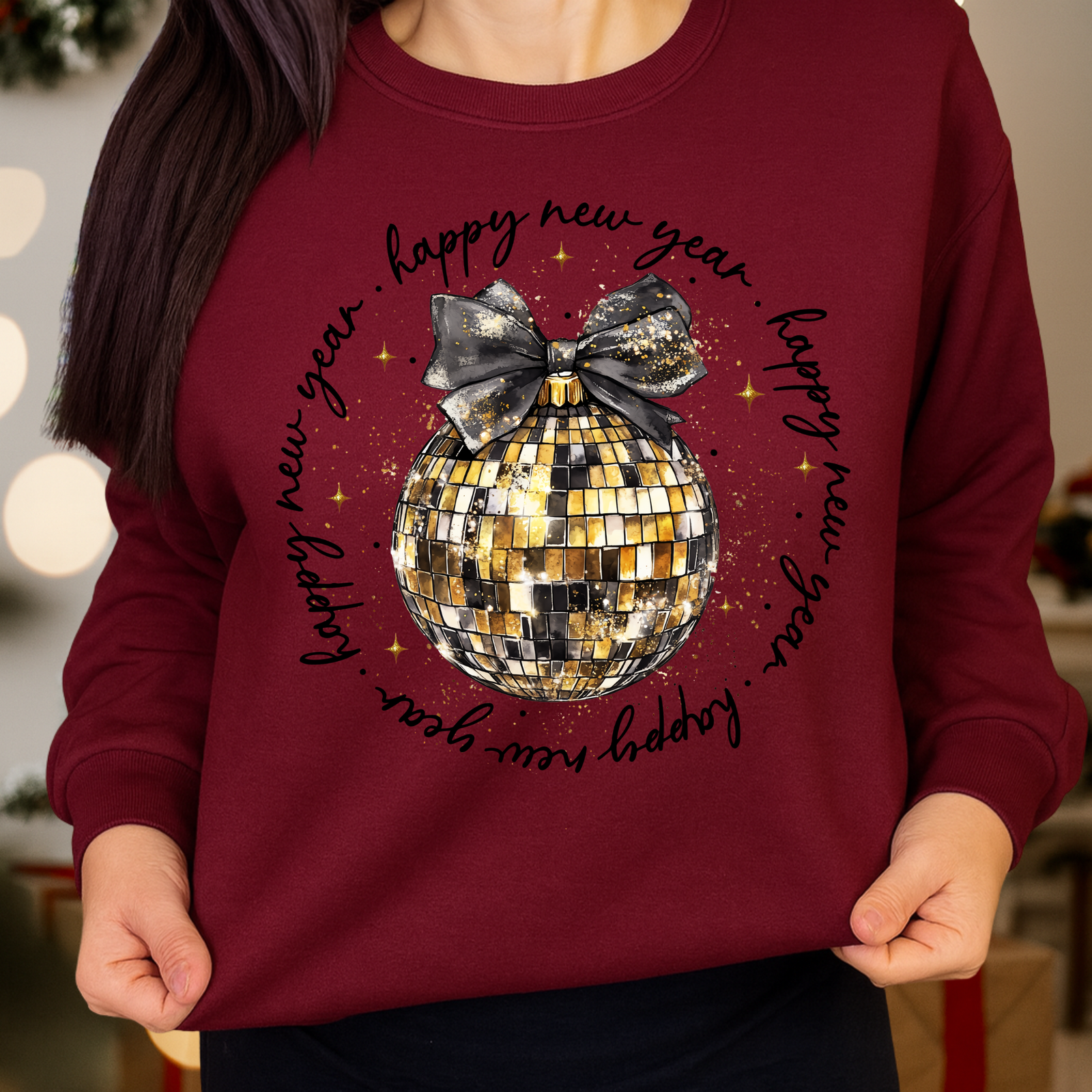 Maroon sweatshirt with a disco ball and 'Happy New Year' text, worn by a person.
