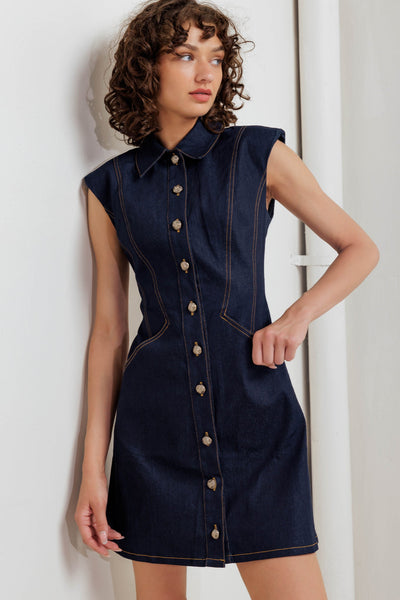 Woman wearing a navy denim dress with buttons against a white background