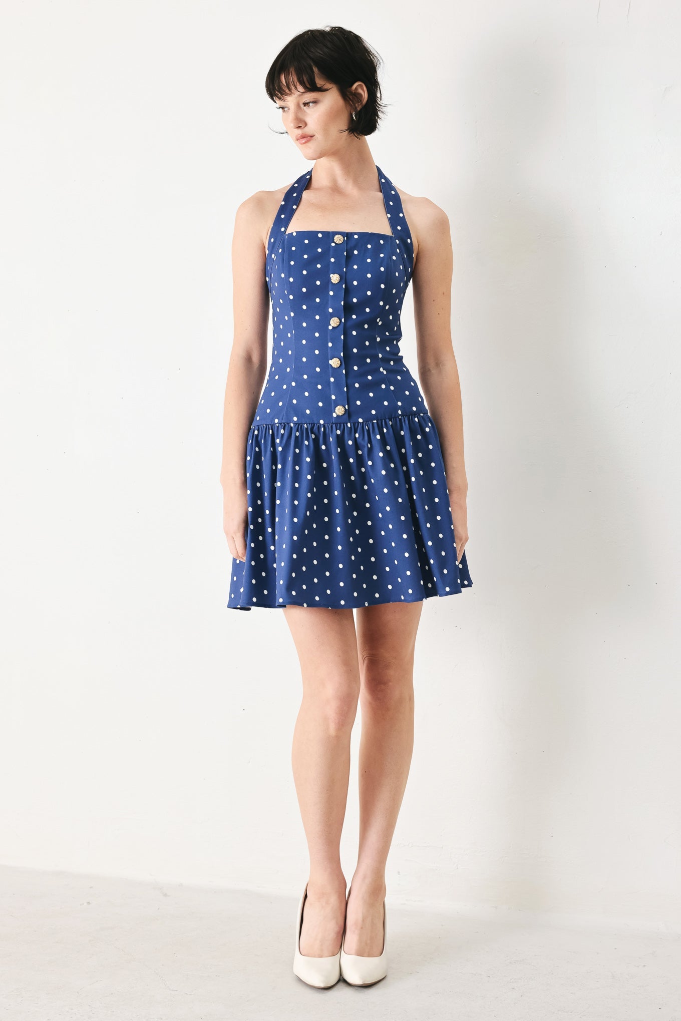 Woman wearing a blue polka dot dress against a white background