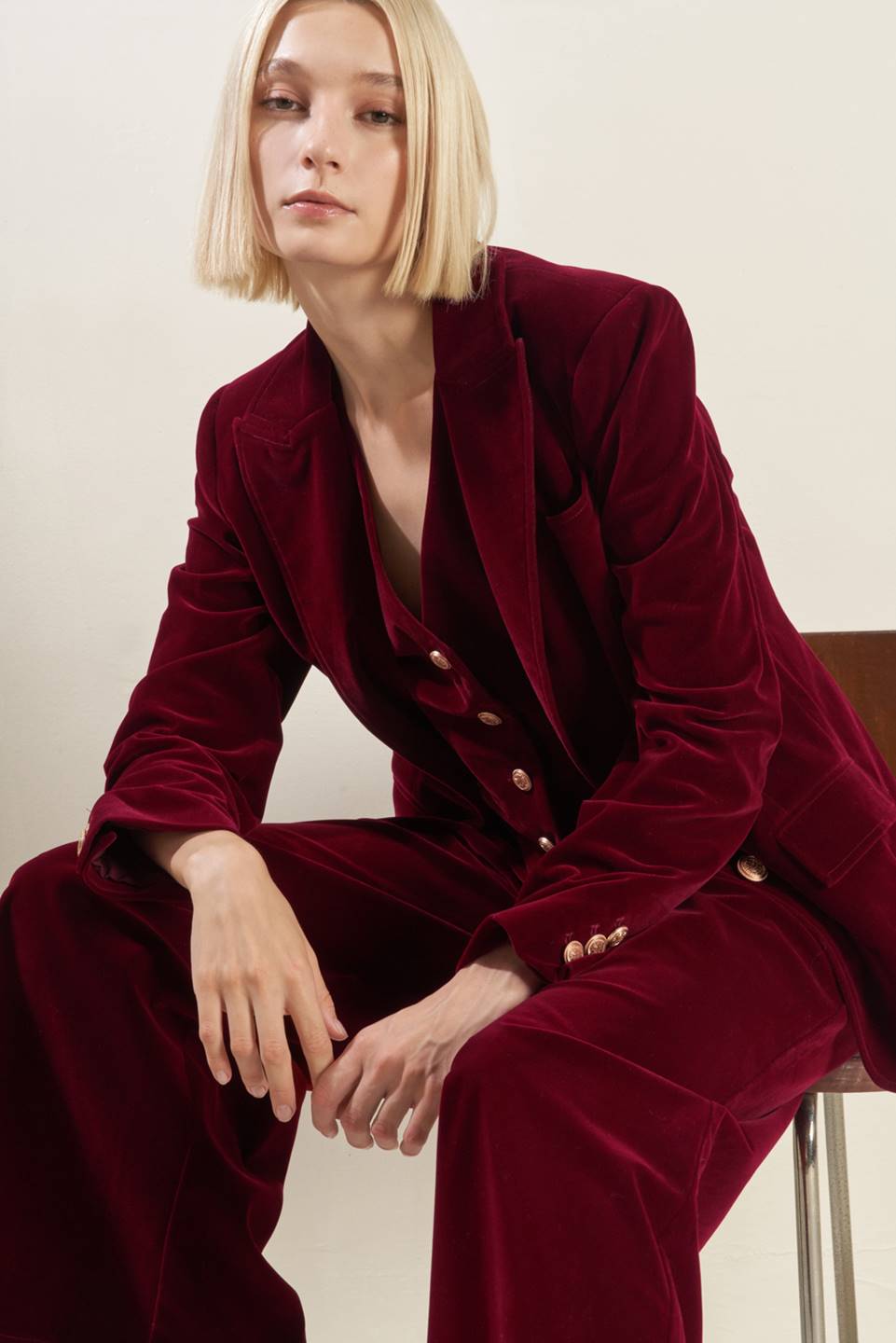 Person wearing a burgundy velvet suit sitting against a plain background