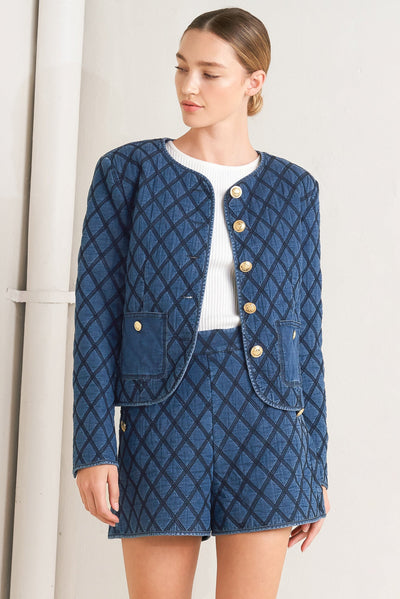 Woman wearing a blue quilted jacket and shorts set against a white background