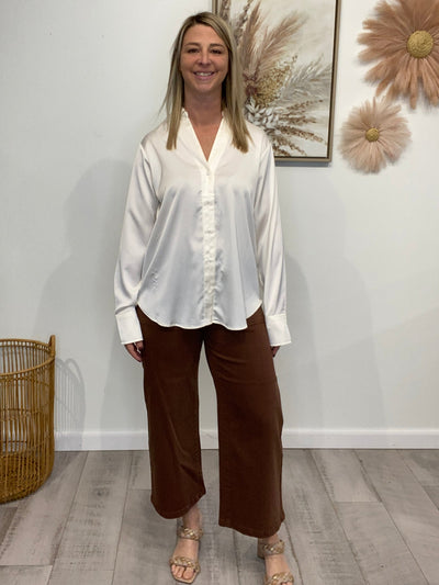 Person wearing a white shirt and brown pants standing in a room with decorative elements.
