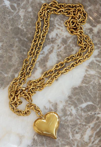 Gold chain necklace with a heart pendant on a marble surface