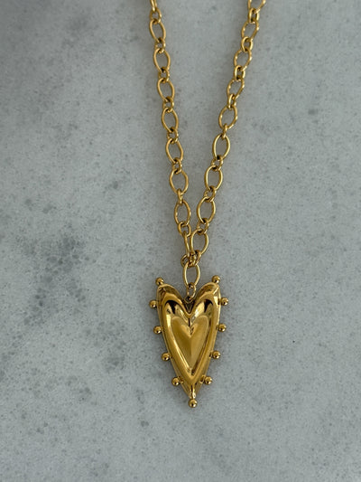 Gold heart-shaped pendant necklace on a gray background