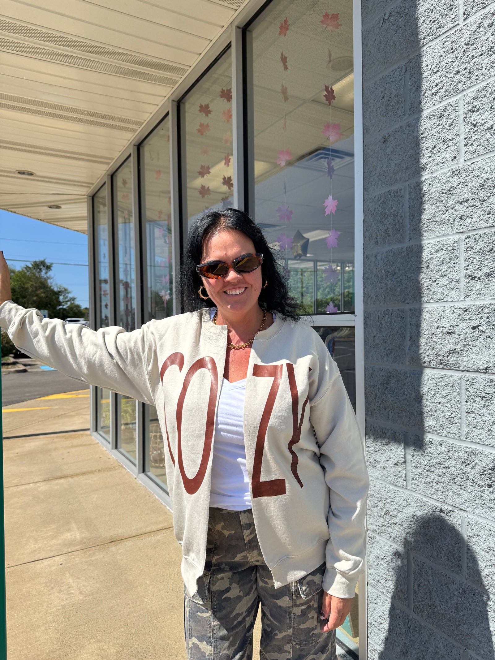 Person wearing a hoodie with a design on it, standing outdoors near a glass structure.