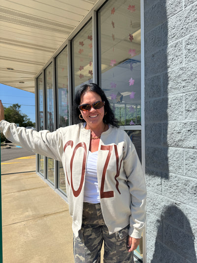 Person wearing a hoodie with a design on it, standing outdoors near a glass structure.