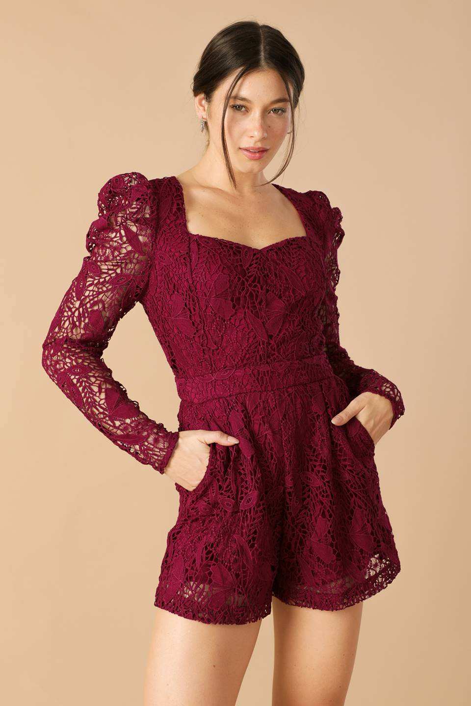 Woman wearing a burgundy lace dress against a beige background