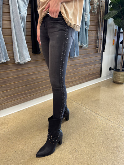 Person wearing black knee-high boots and dark jeans in a store setting.