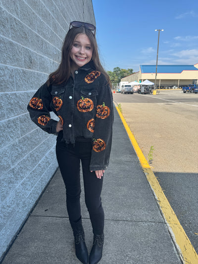 Person wearing a black jacket with orange patterns on a street