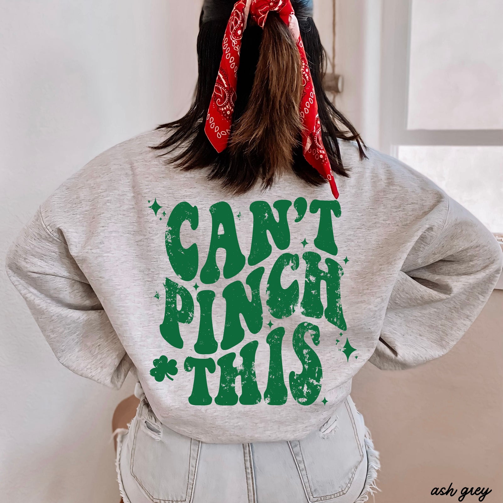 Person wearing a gray sweatshirt with green text 'CAN'T PINCH THIS' and a red bandana.